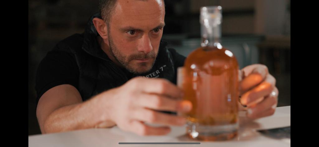 Chapter 7 bottling services. A photo of Sebastian meticulously applying a label on a bottle of Chapter 7 Whisky